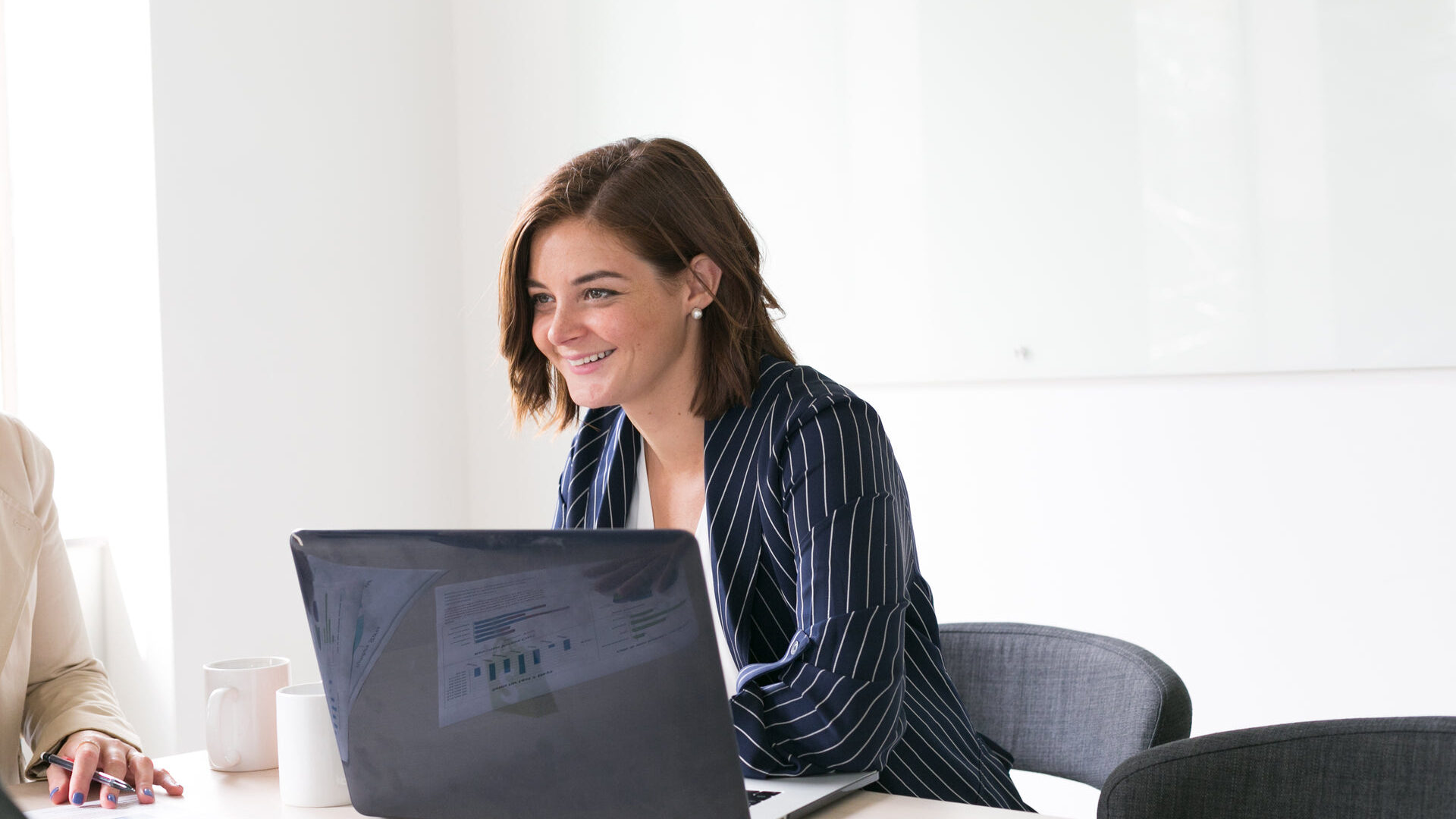 Femeie care lucrează la laptop, într-un birou luminos.