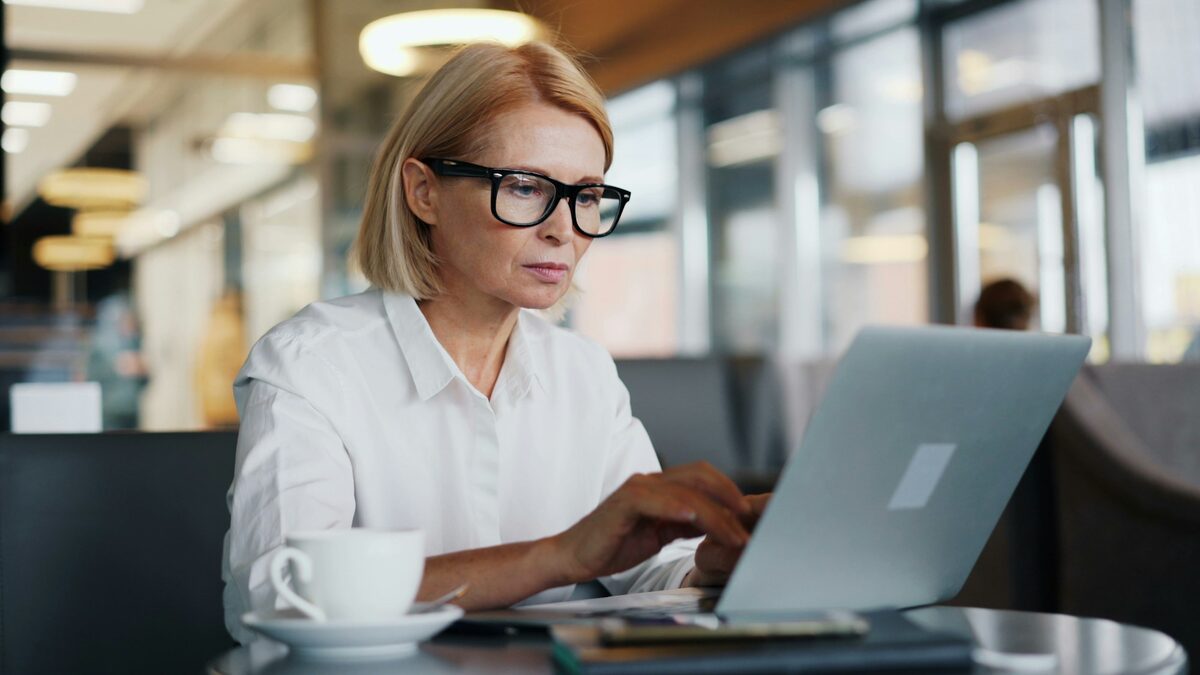 Angajată de birou cu ochelari care lucrează pe laptop la tabelele pivot din Excel