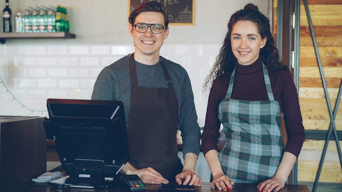 Doi patroni zâmbitori la tejgheaua cafenelei lor, o firmă mică în care inteligența artificială poate prelua munca repetitivă