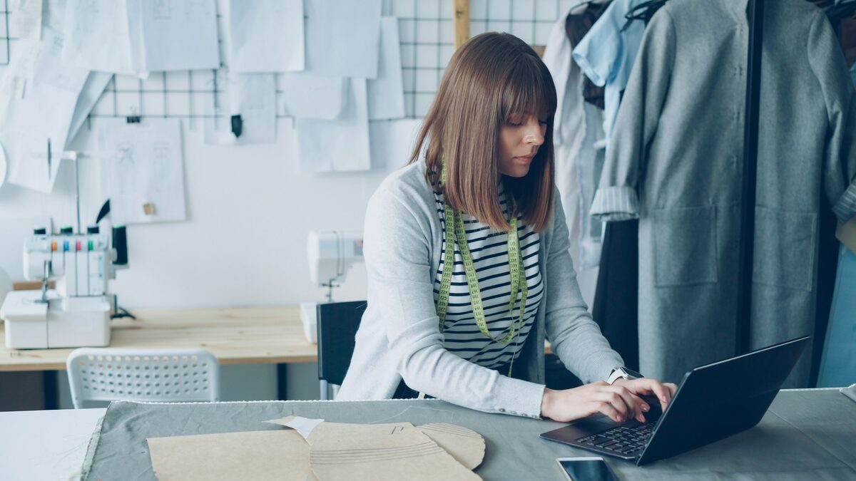Freelanceră în atelierul de design, care își aranjează pe laptop portofoliul de freelancer
