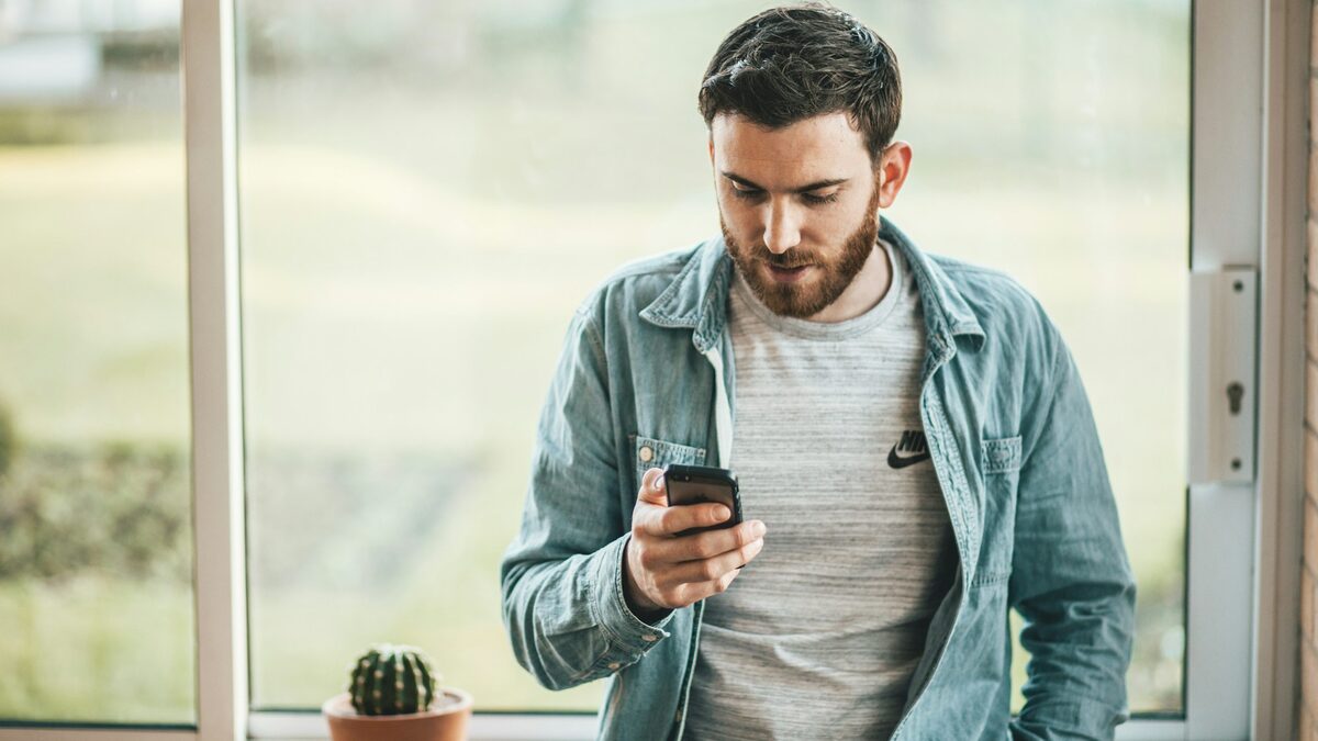 Meseriaș în cămașă de lucru care scrie pe telefon mesajele către clienți pentru meseriași