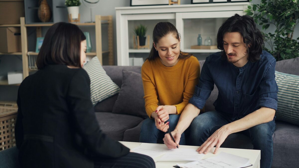 Agentă imobiliară care completează actele cu un cuplu de clienți, o agenție imobiliară care poate folosi AI pentru cereri și vizionări