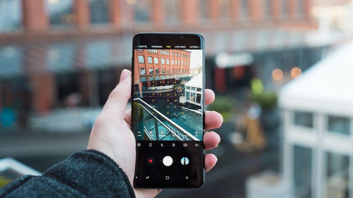 Mână care ține un telefon Samsung și face o fotografie pe care o poate edita apoi cu Galaxy AI