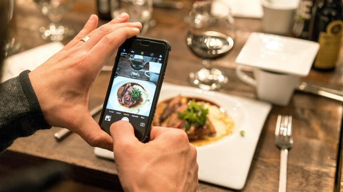 Turist care îndreaptă camera telefonului spre farfurie la un restaurant din străinătate, ca să afle cu Google Lens ce a comandat