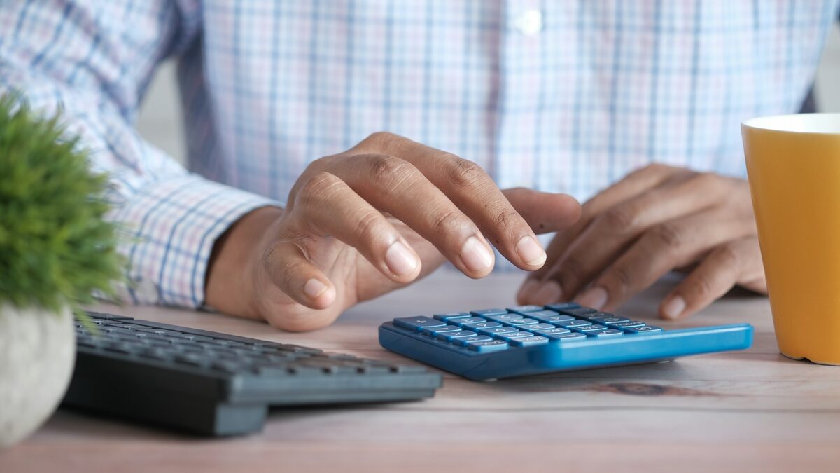 Mâini care lucrează cu un calculator de birou, ca atunci când calculezi timpul economisit cu automatizările