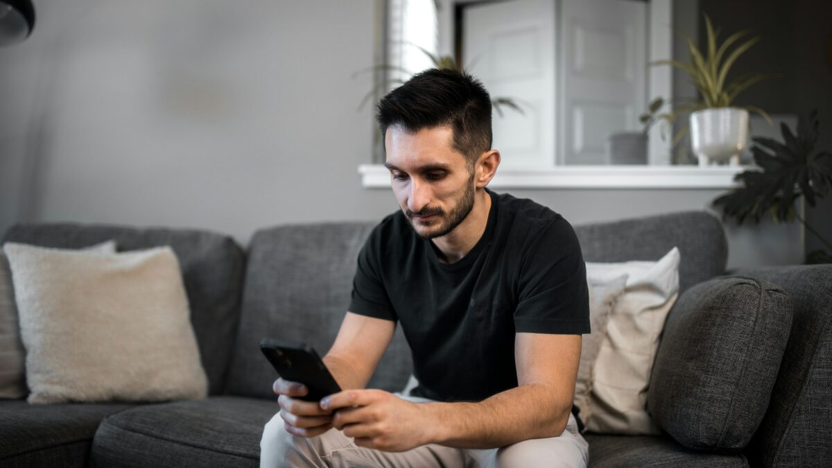 Bărbat care compară pe telefon comentariile unui produs ca să descopere recenziile false