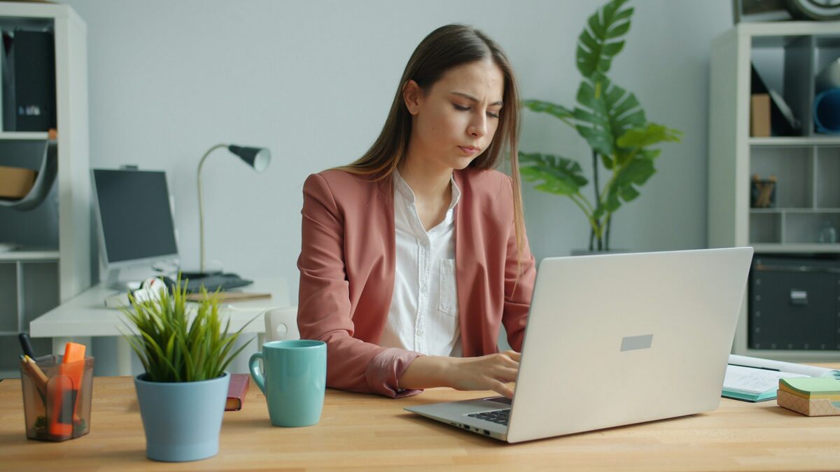 Femeie la birou care folosește ChatGPT în limba română pe laptop pentru un e-mail de serviciu