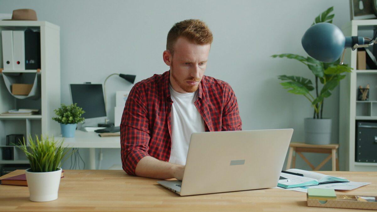 Bărbat la masa de lucru de acasă care învață cum se folosește ChatGPT pe laptop