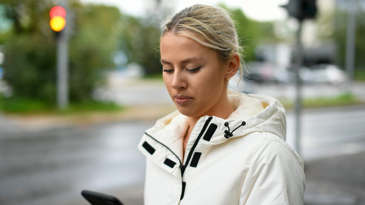 Femeie pe stradă care folosește Gemini de la Google pe telefon, cerându-i un traseu prin oraș