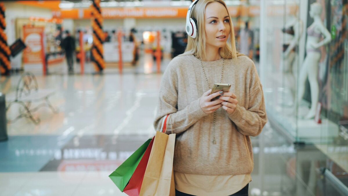 Clientă mulțumită cu sacoșe de cumpărături care scrie pe telefon, ca să obții mai multe recenzii Google