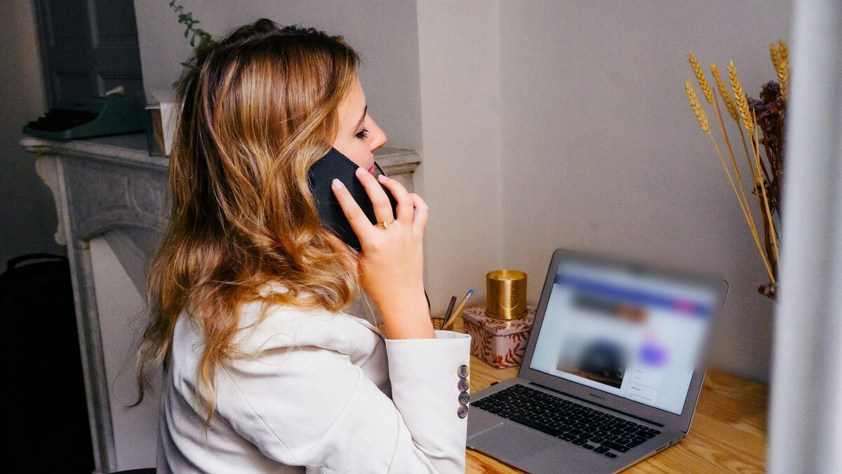 Antreprenoare care sună de la birou, lângă laptop, ca să revină la clienții care au tăcut după ofertă