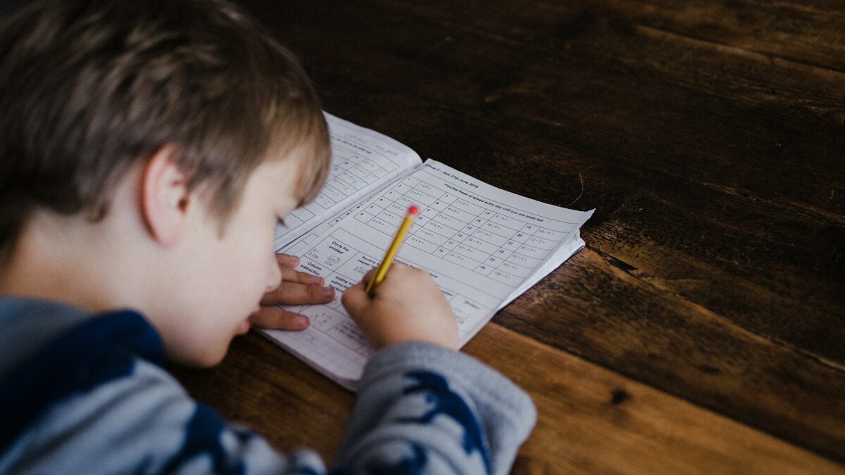 Elev care rezolvă în caiet o problemă de matematică, pe care o poate verifica apoi cu o aplicație de AI