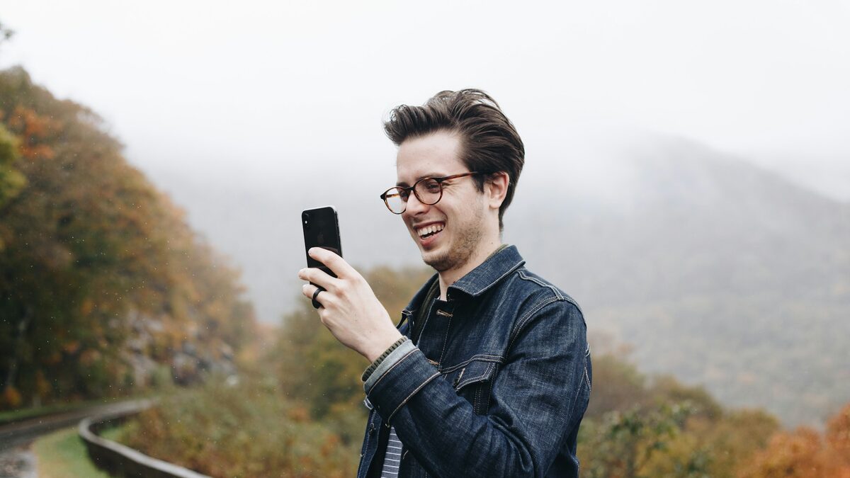 Tânăr cu ochelari care privește zâmbind pe telefon avatarul cu AI creat din poza lui