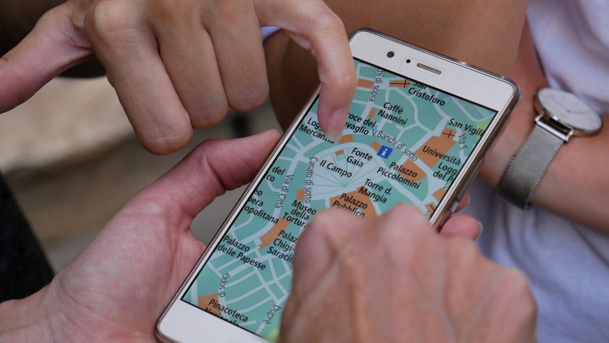 Mâini care caută pe hartă, pe telefon, o firmă din apropiere, unde contează profilul firmei pe Google Maps