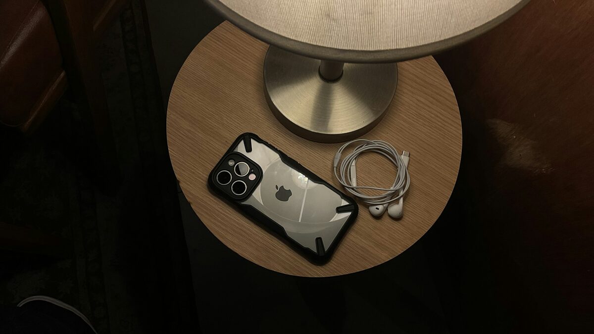 Telefon pus pe noptieră lângă veioză, un obicei obișnuit la încărcarea telefonului peste noapte