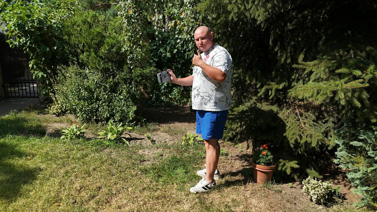 Bunic în grădină care ține telefonul aproape de gură și trimite mesajele vocale pe WhatsApp