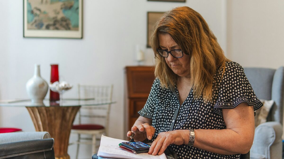 Femeie acasă care învață limba italiană pentru începători cu un asistent AI pe telefon, cu caietul de notițe