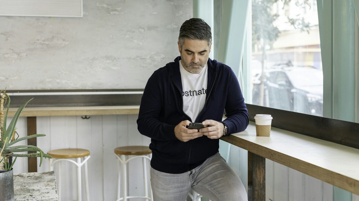 Bărbat într-o cafenea care citește știri pe telefon, întrebându-se dacă AI-ul e doar o modă