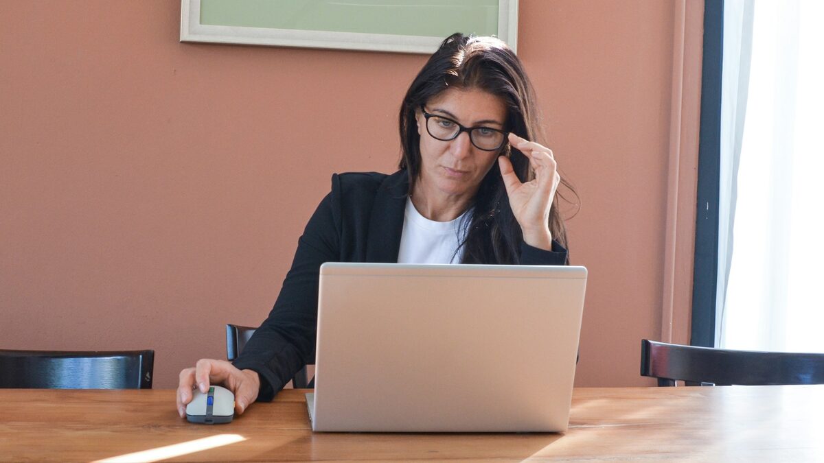Femeie care citește atent răspunsul unui asistent AI pe laptop, întrebându-se dacă AI-ul gândește ca un om