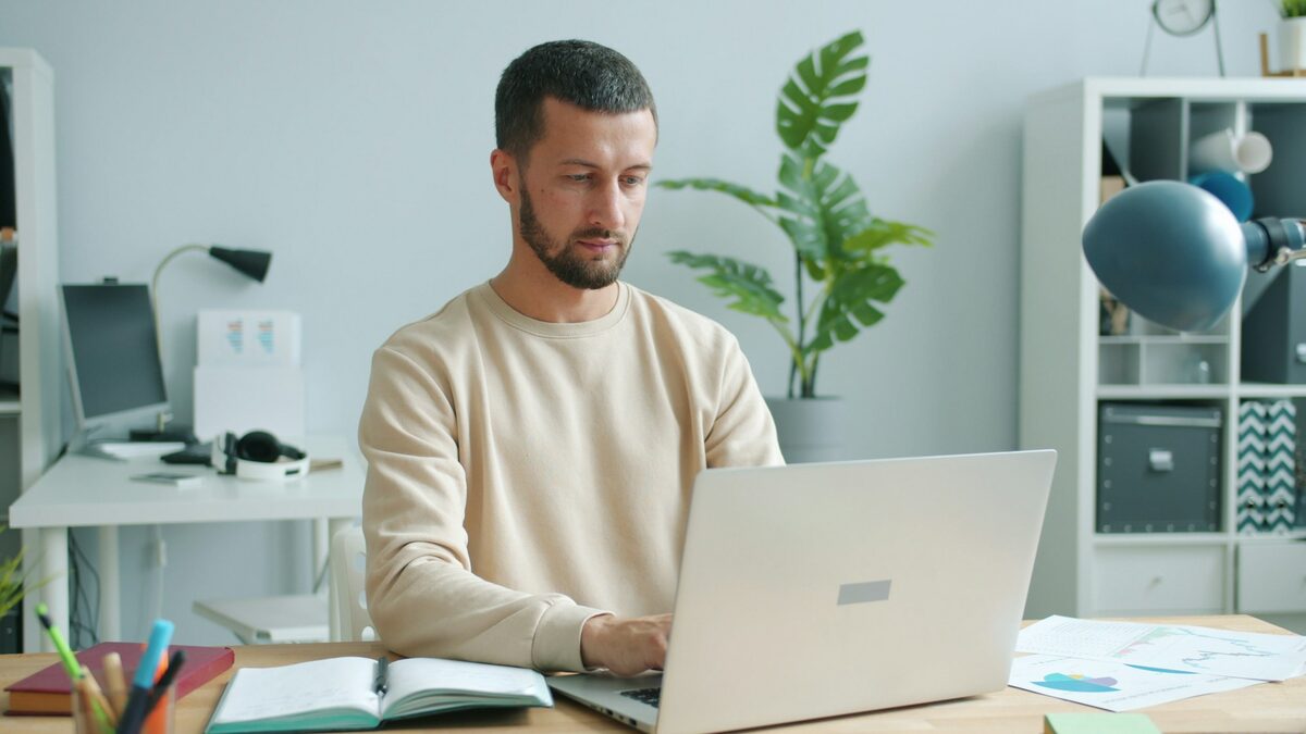 Angajat la birou care folosește AI la locul de muncă pentru o ciornă de e-mail, pe laptopul de serviciu