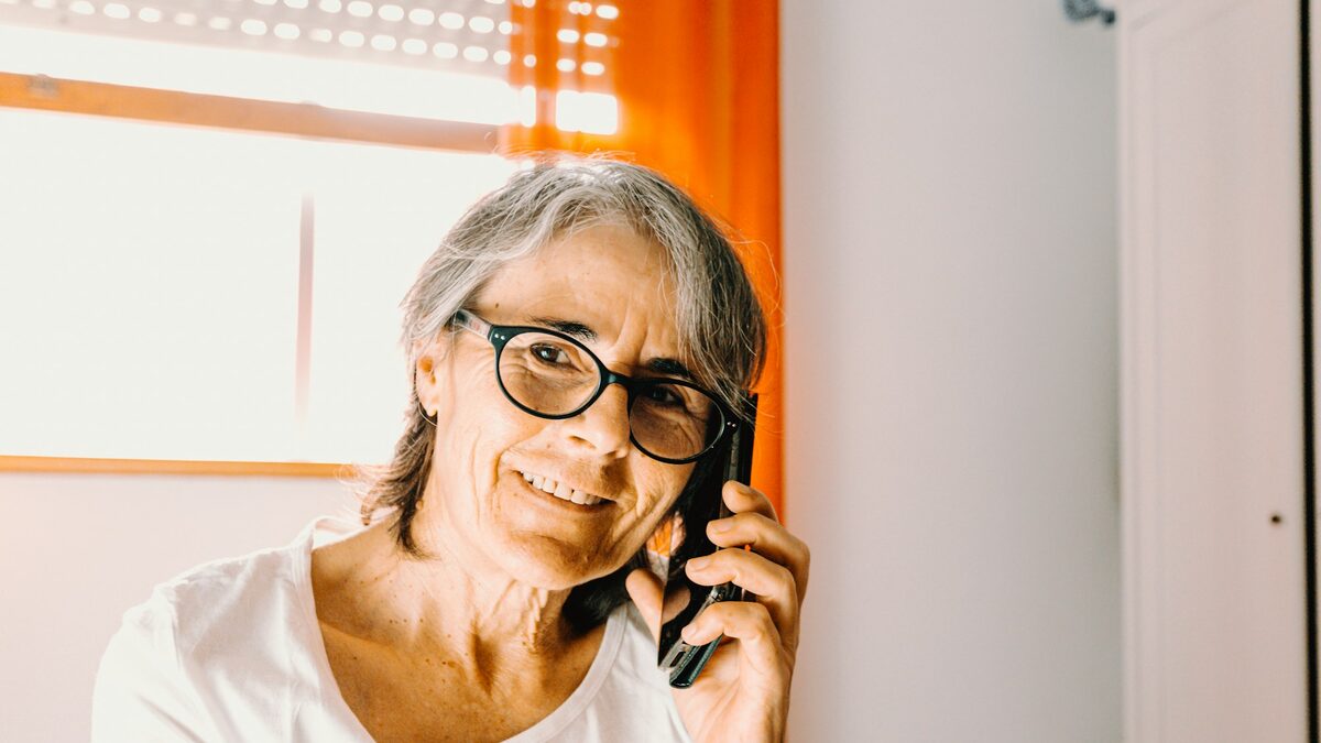 Bunică la telefon, atentă la apelant, care cere un cod de siguranță în familie