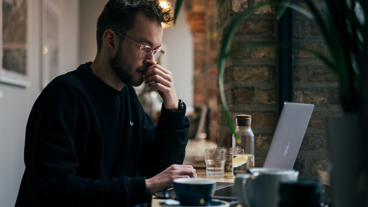 Bărbat îngândurat la laptop care verifică dacă datele lui apar într-o breșă și ce parole trebuie să schimbe