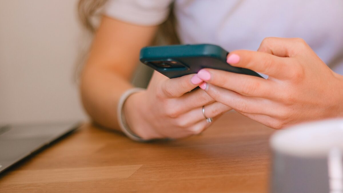 Mâini care ajustează setările de confidențialitate WhatsApp pe un telefon, la masă