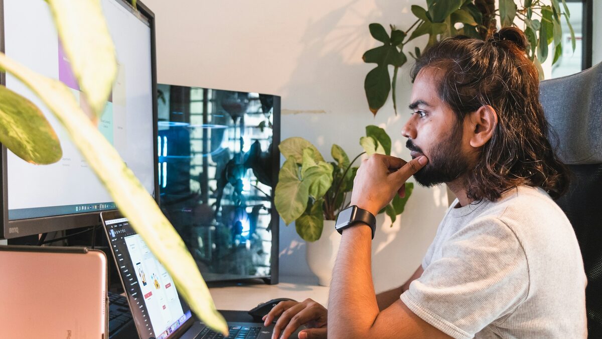 Bărbat la biroul de acasă, cu laptopul și monitorul alături, care alege browserul potrivit