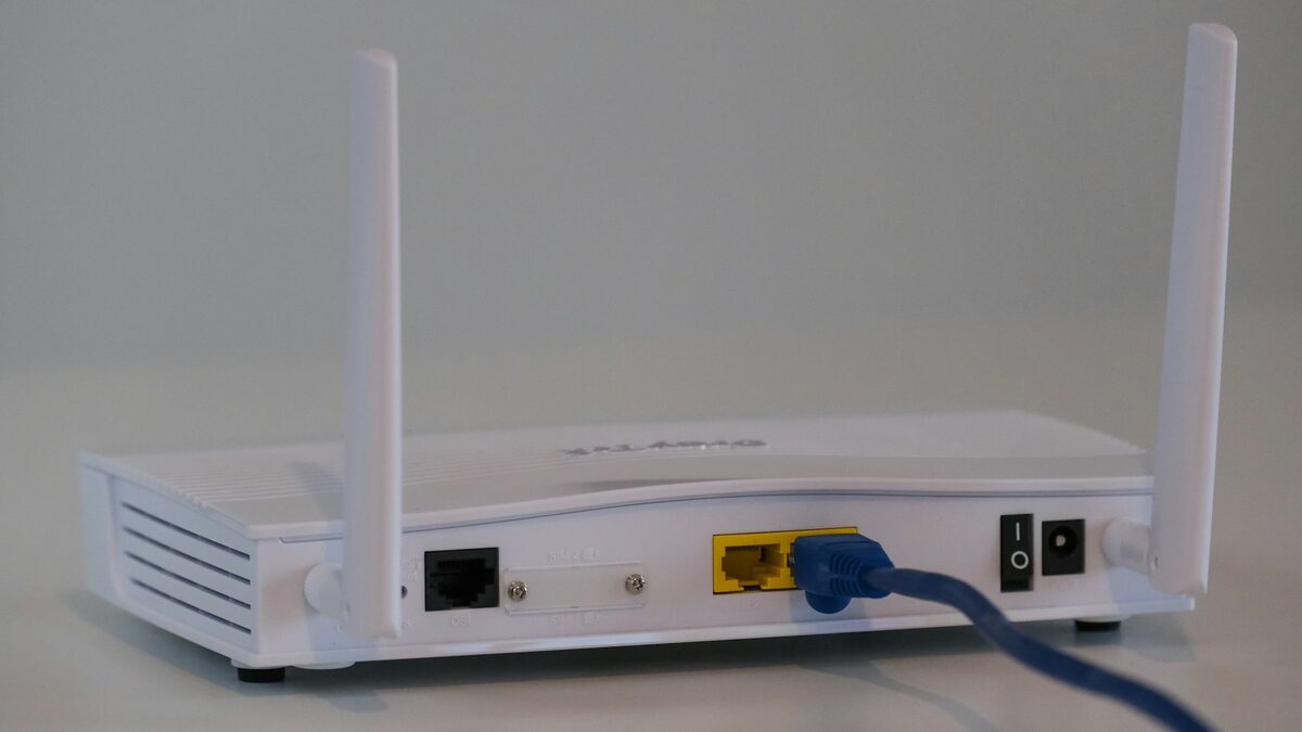 Router alb conectat prin cablu, pentru comparația fibra optică sau internet 5G acasă